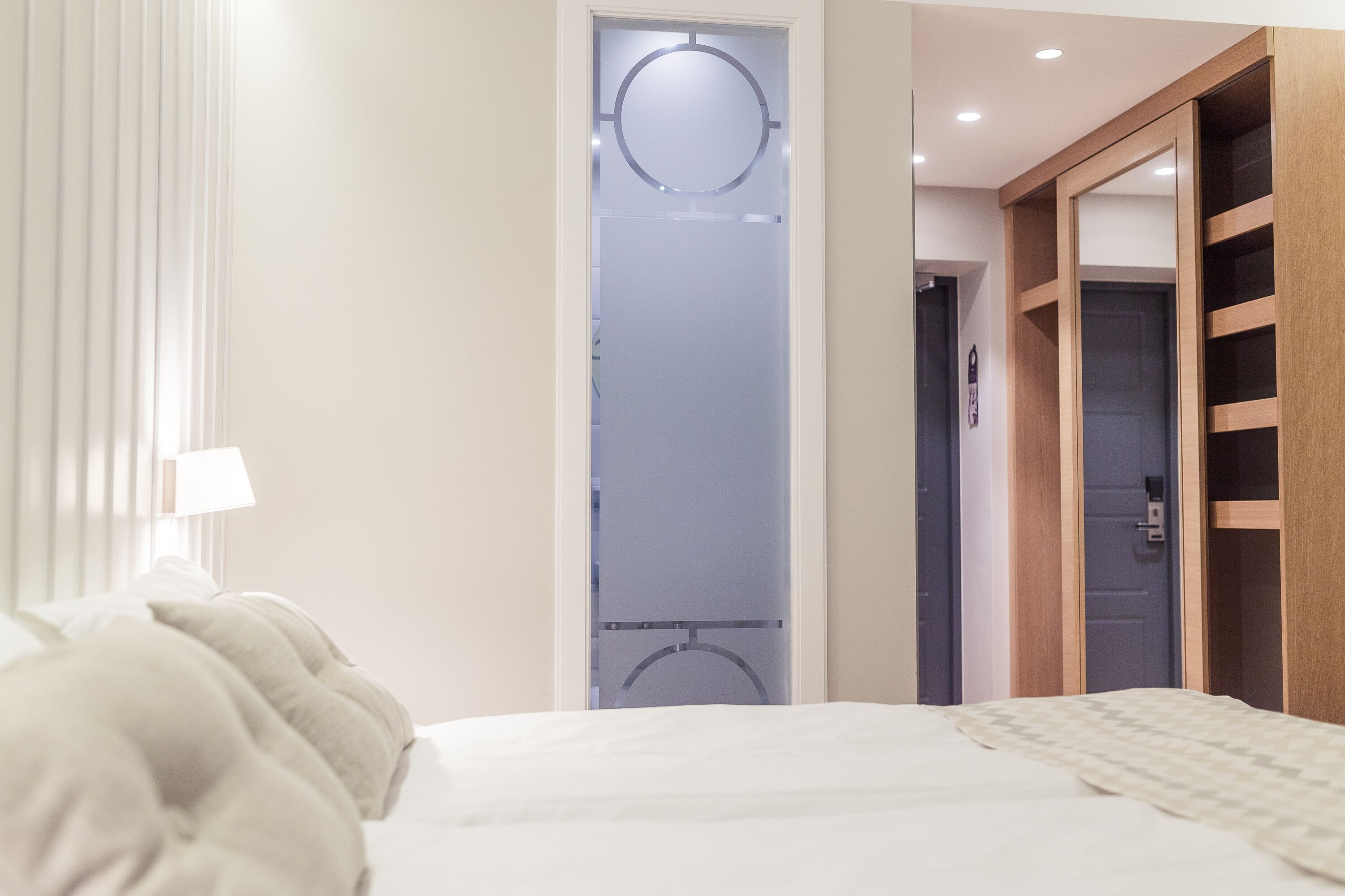A hotel room with a bed, a wardrobe, and a door leading to a bathroom.