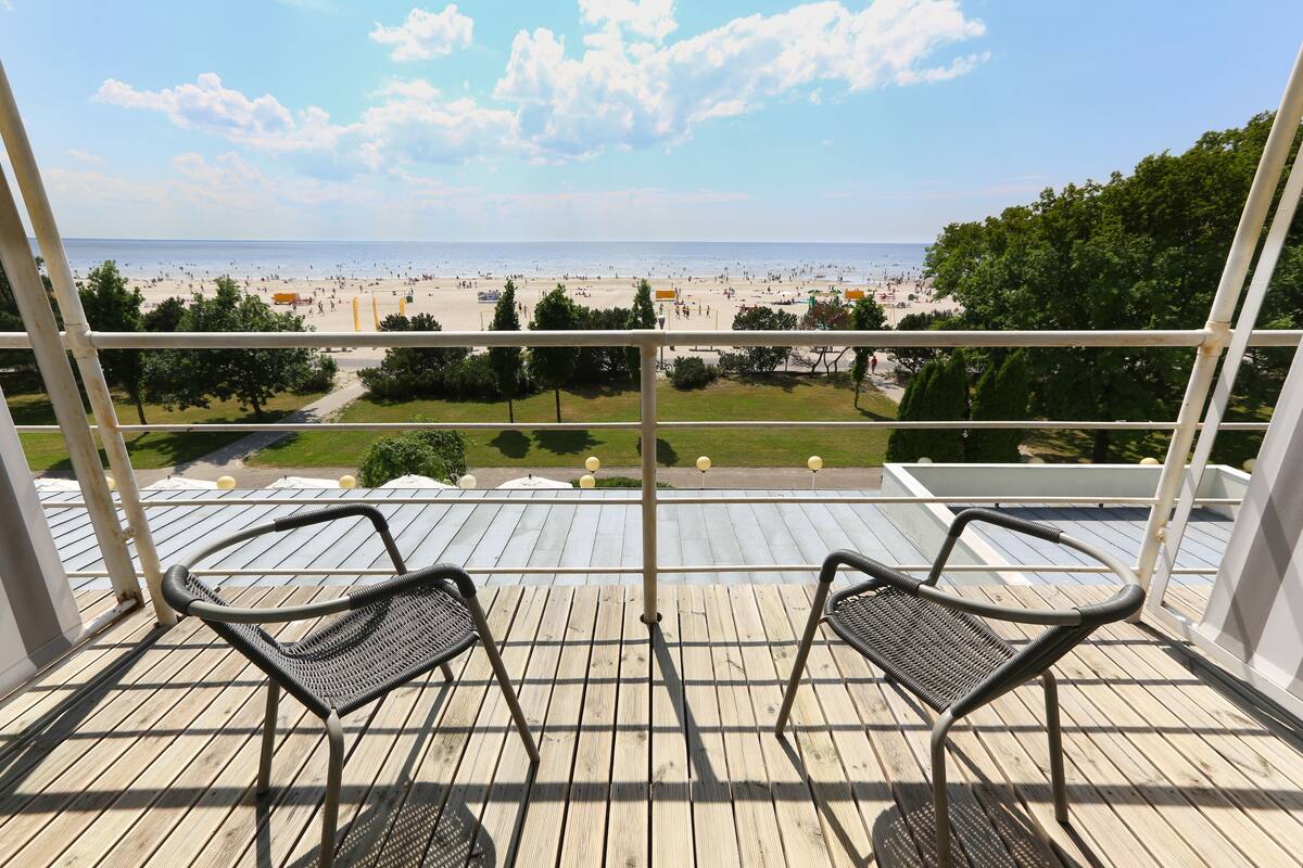 A balcony with two chairs overlooking a beach.