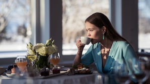 A dining table with a meal, a glass of white wine, and a vase of flowers. - Rannahotell (Parnu)