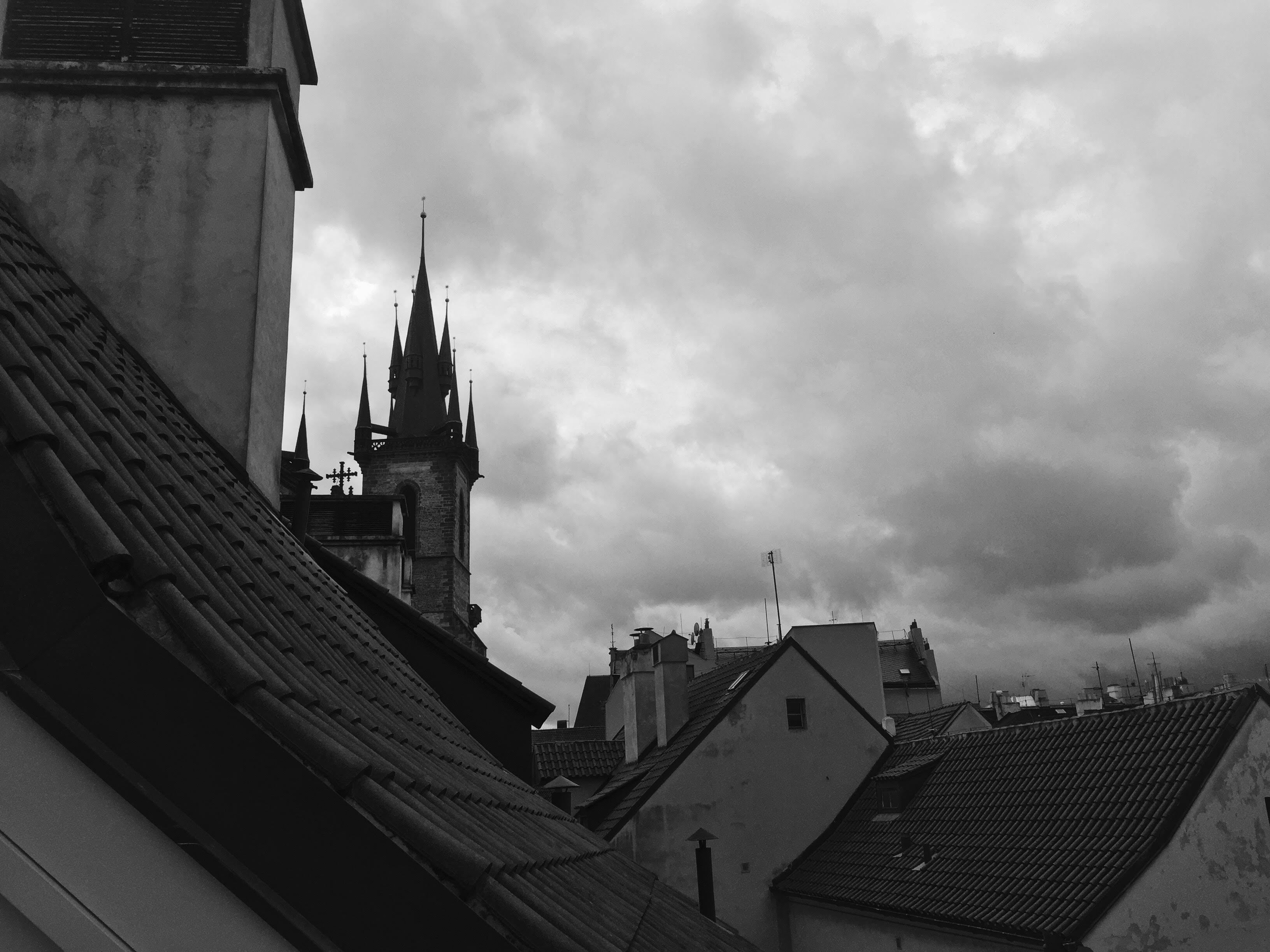 A black and white view of a historic building with a prominent tower and steeply pitched roofs.