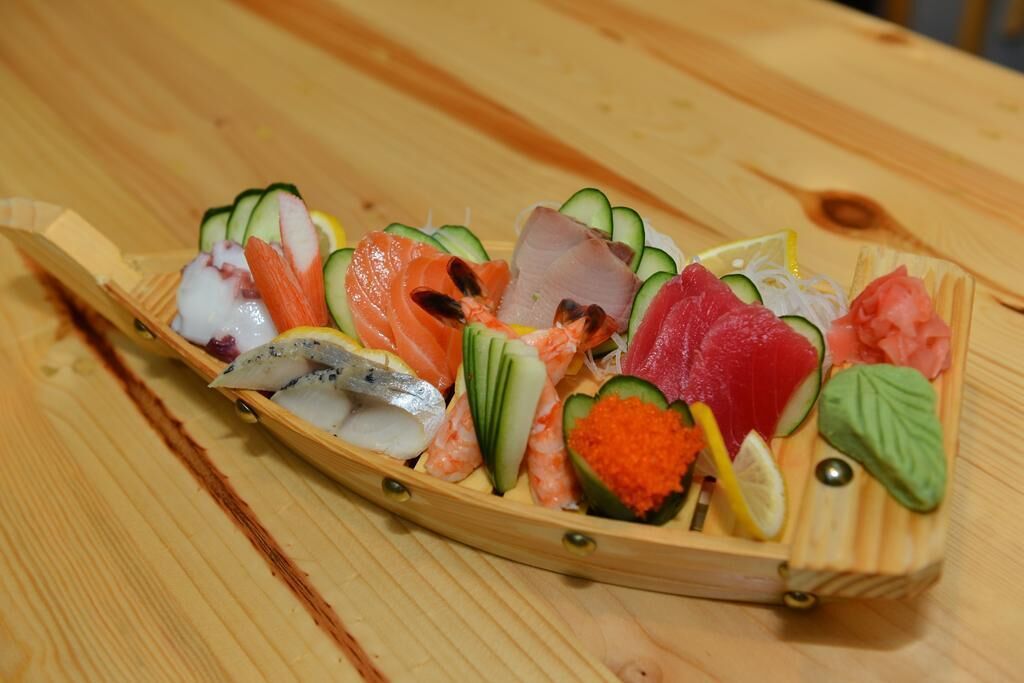 Een bootvormig houten schaal met verschillende soorten sushi.