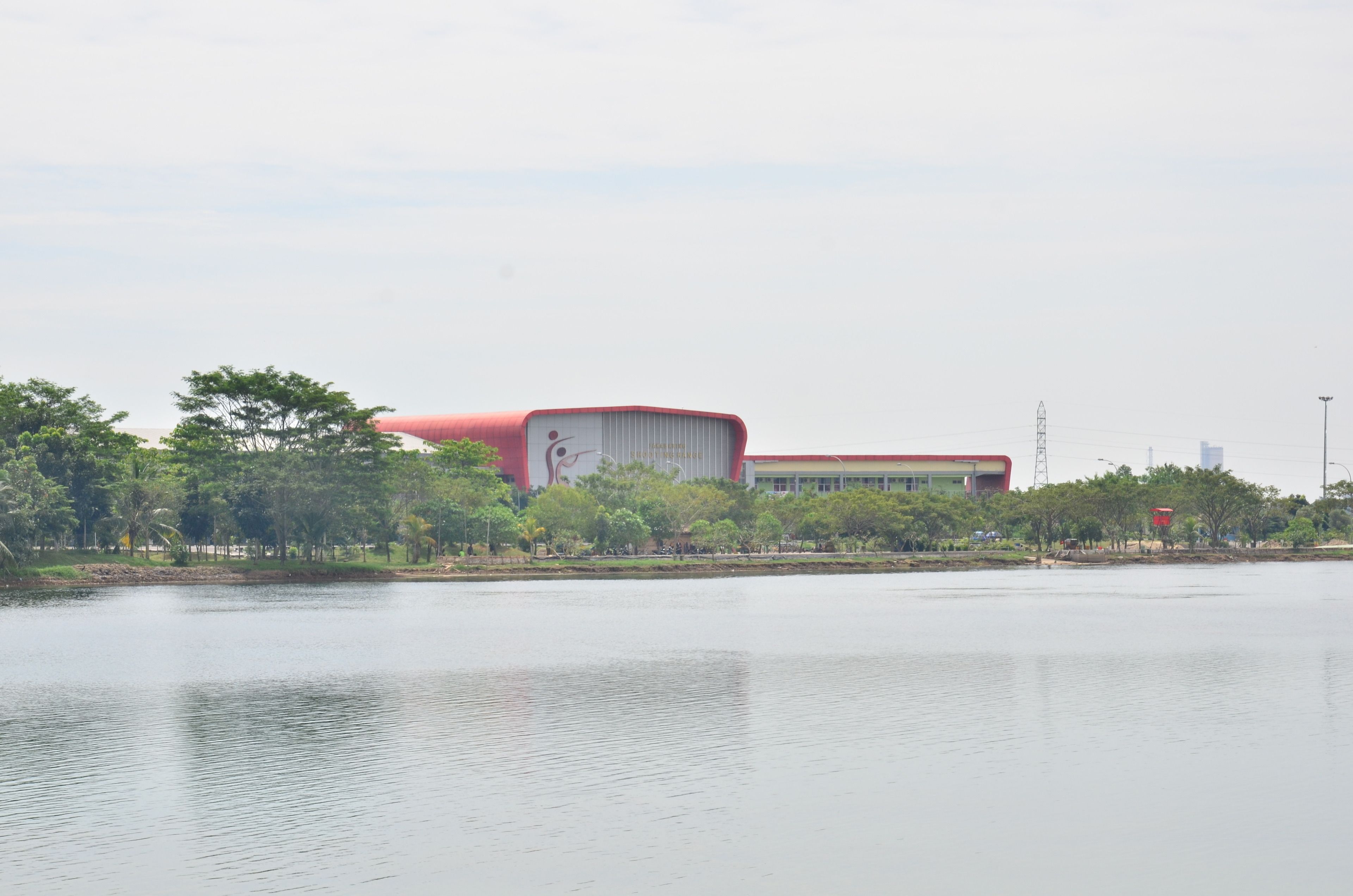 Un bâtiment moderne, doté d’un toit rouge et de murs blancs, situé au bord d’une étendue d’eau paisible.
