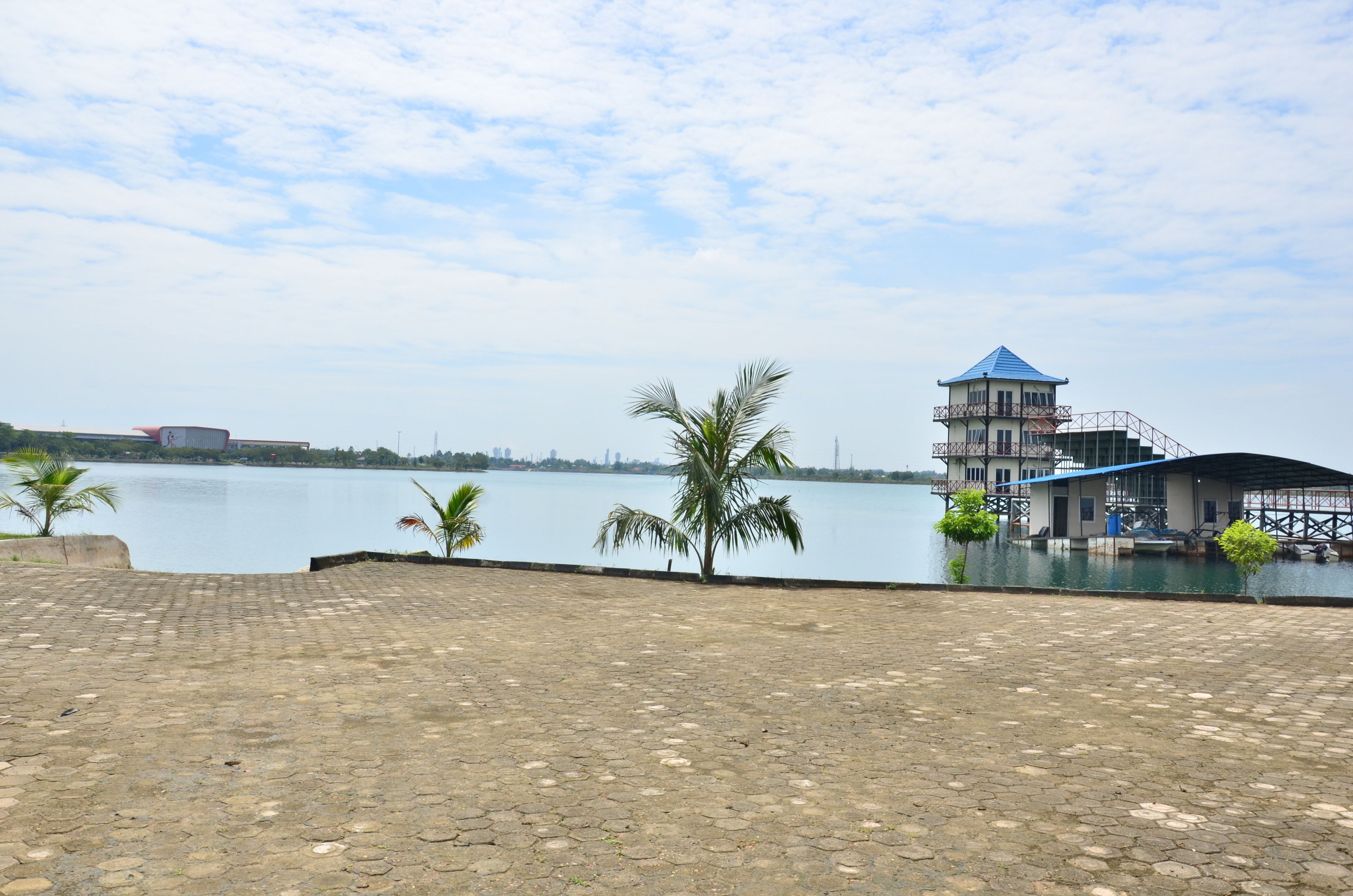 A waterfront property with a dock, a building with a blue roof, and palm trees.