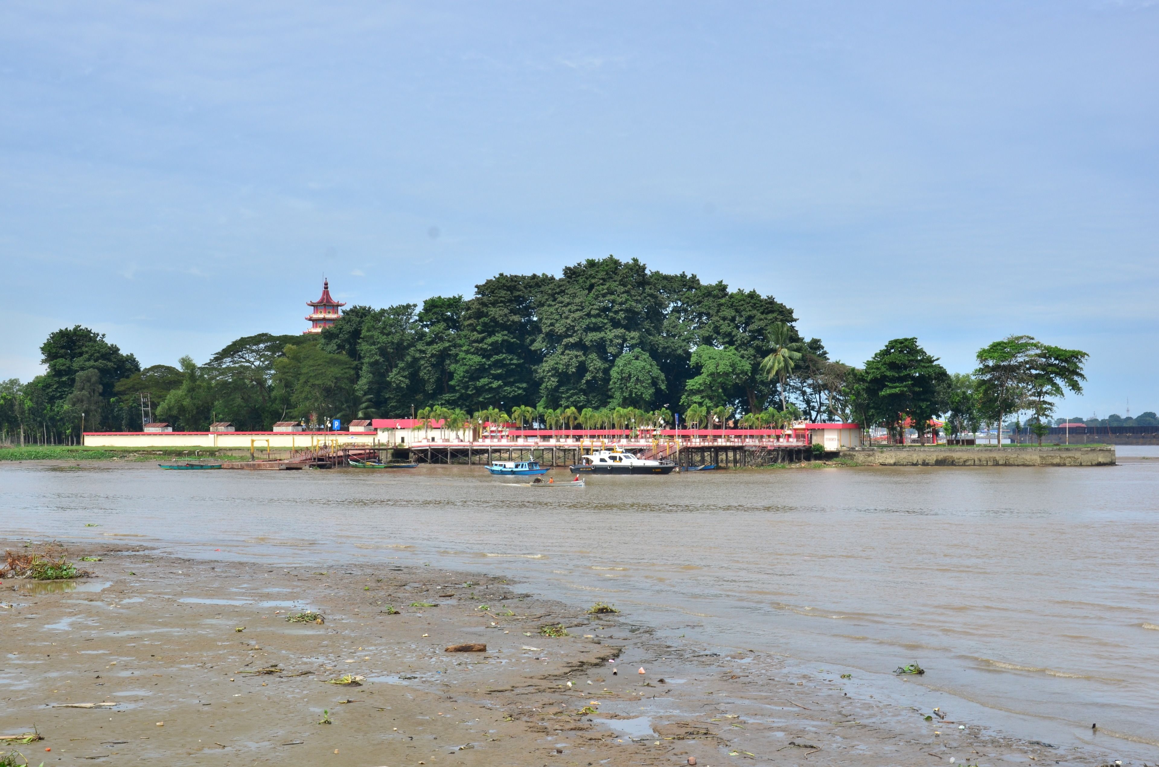 A riverside view with a bridge, boats, and a pagoda.