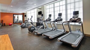 Une salle de sport équipée de tapis de course, de ballons d'exercice et d'appareils de musculation.