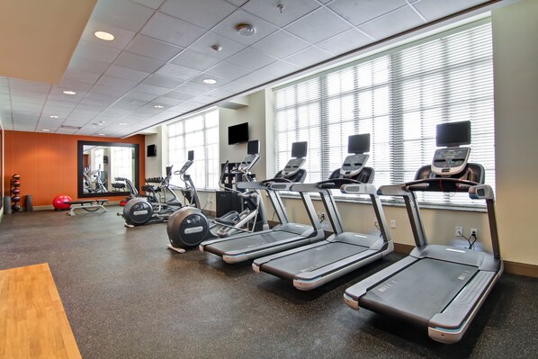 Un gimnasio con cintas de correr, pelotas de ejercicios y máquinas de pesas.