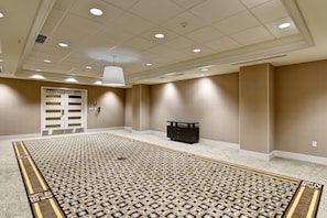 A spacious room with a patterned carpet, beige walls, and a ceiling with recessed lighting.