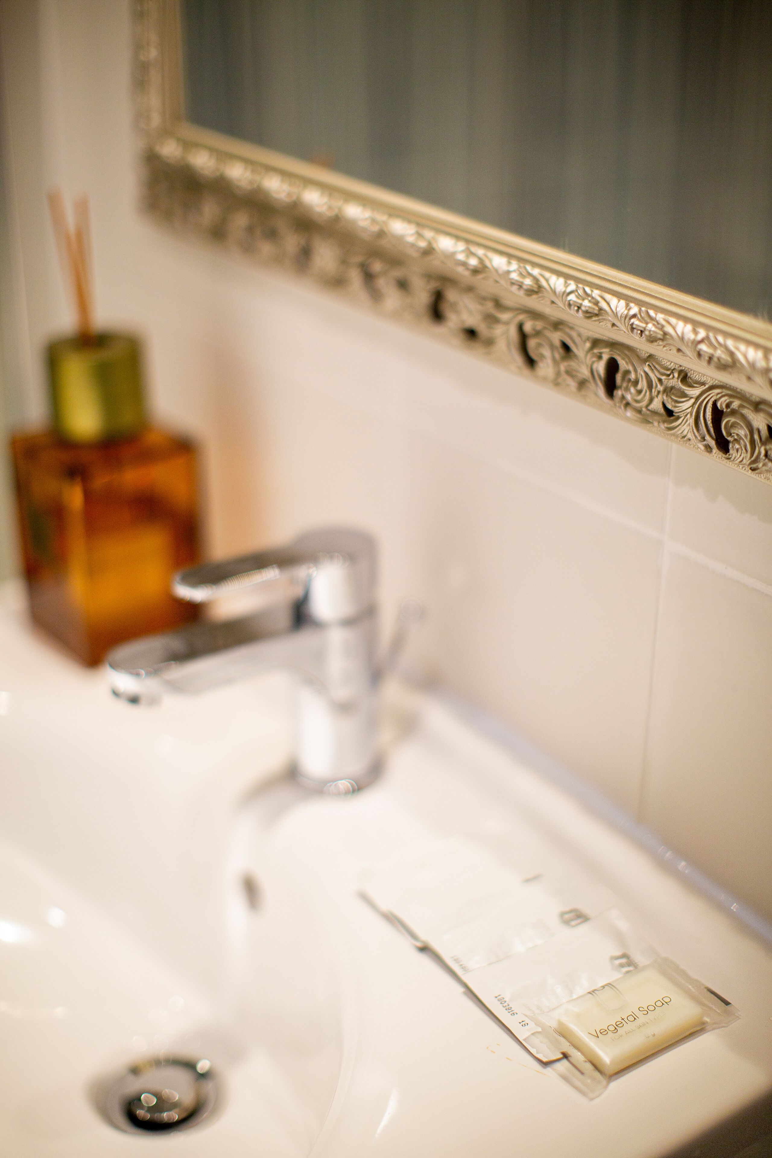 Un lavabo in bagno con specchio, erogatore di sapone e saponetta.