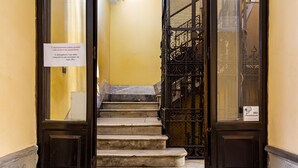 Un conjunto de escaleras de mármol que conducen a una reja de metal negro, con un letrero en la puerta izquierda.