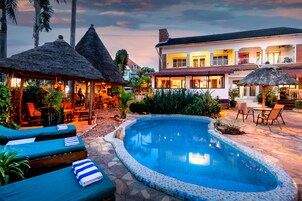 A pool area with lounge chairs and a thatched-roof structure.