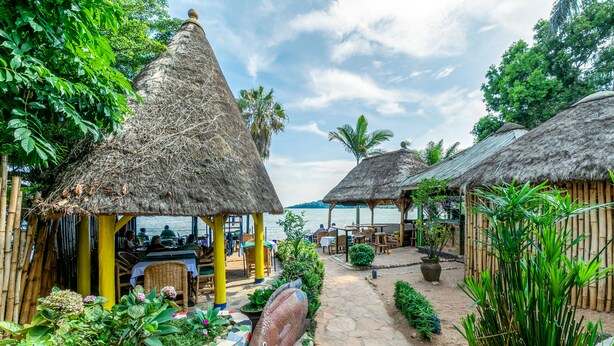 A tropical resort with thatched-roof huts, a stone pathway, and lush greenery. - 2 Friends Beach Hotel (Entebbe)
