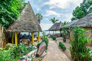 Un complexe hôtelier tropical doté de bungalows aux toits de chaume, d’un sentier pavé de pierres et d’une végétation luxuriante.
