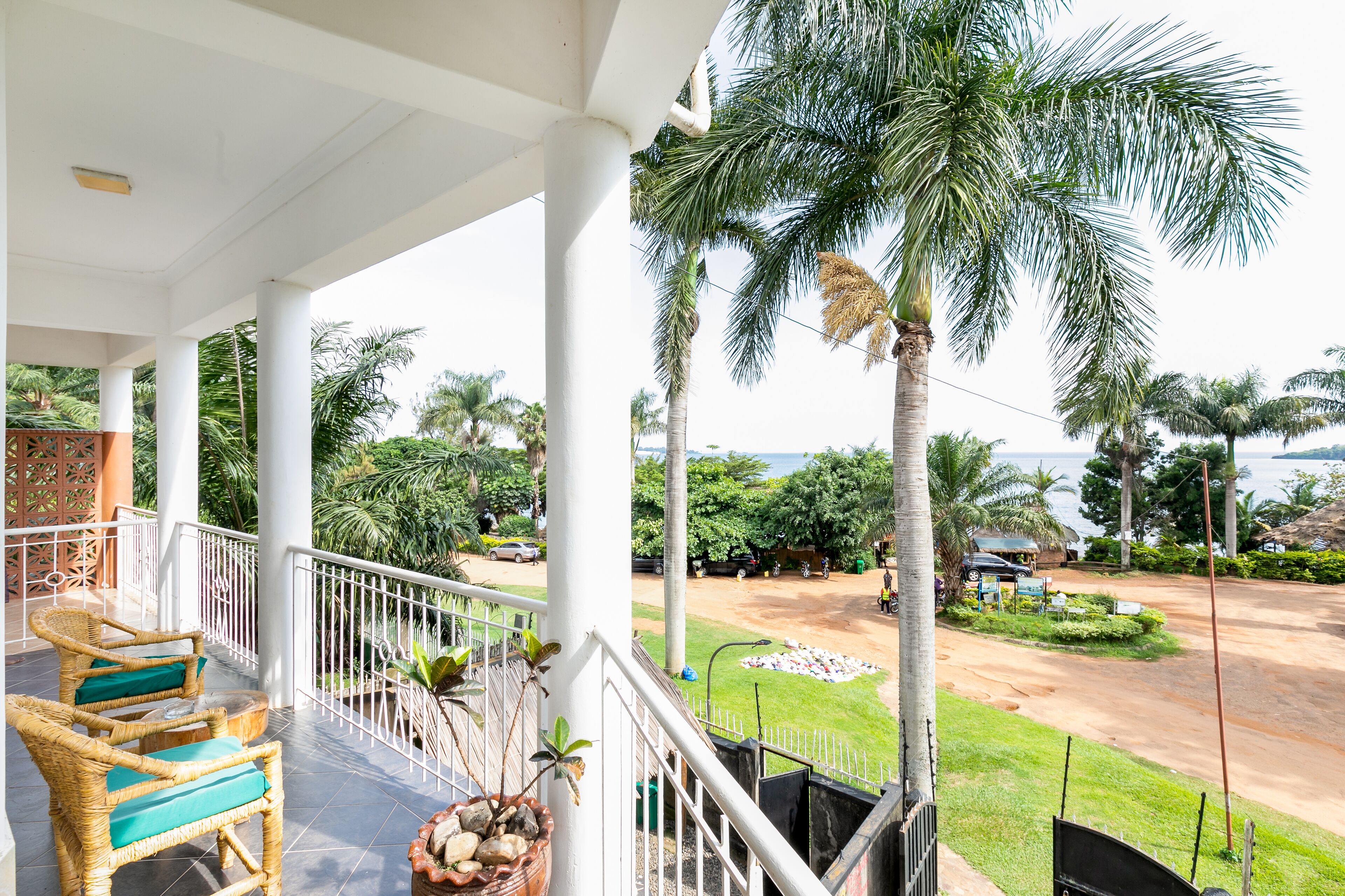 A covered outdoor area with wicker chairs and a view of a road and greenery.