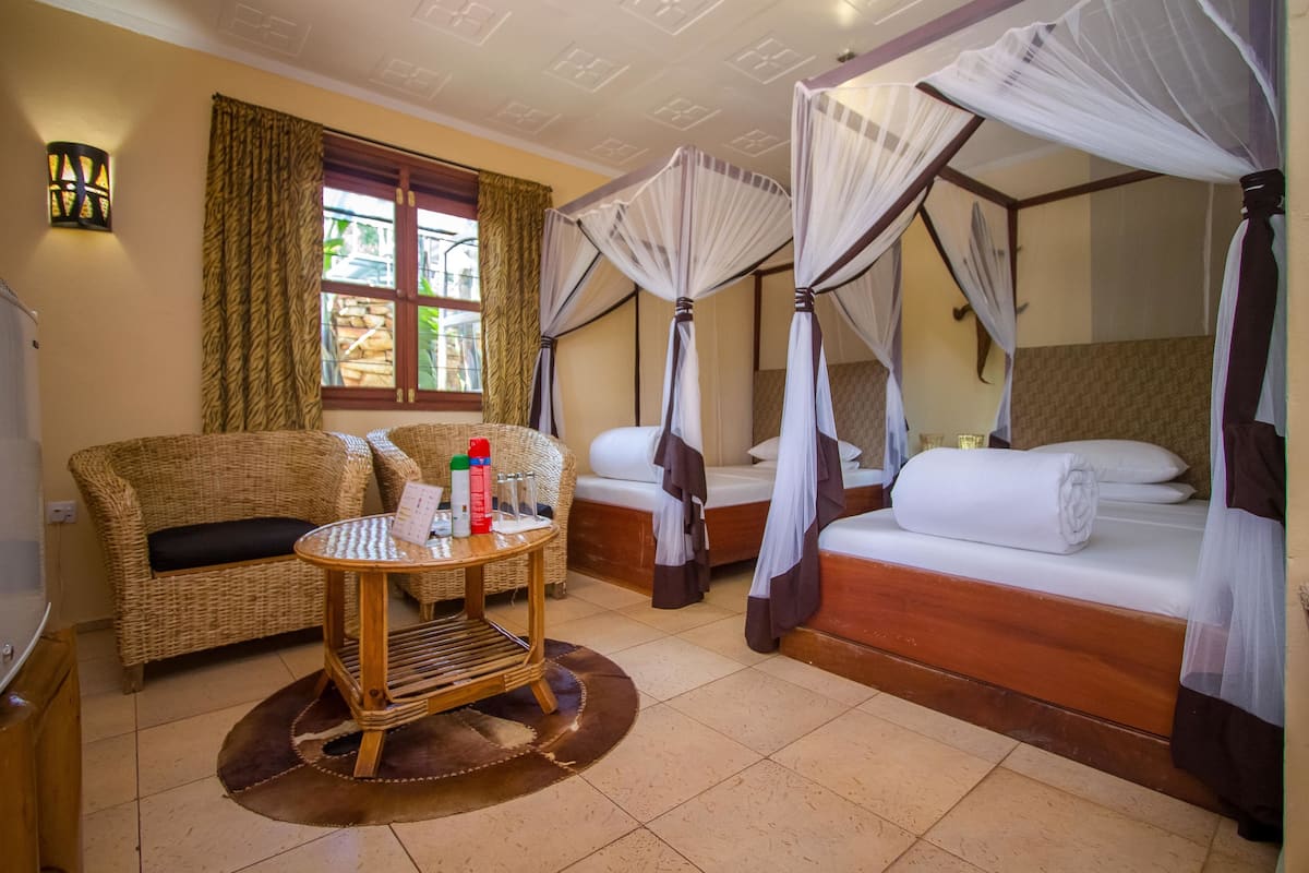 A room with a bed, a sofa, a small table, and a window with curtains.
