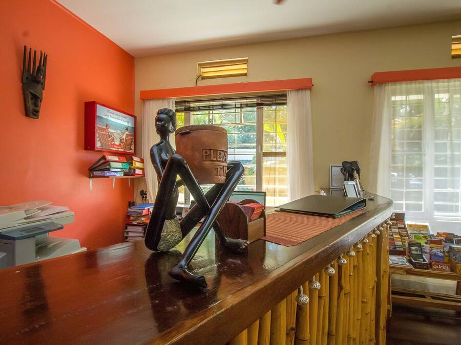 A reception area with a wooden counter, a sculpture, a poster, and a window with curtains.