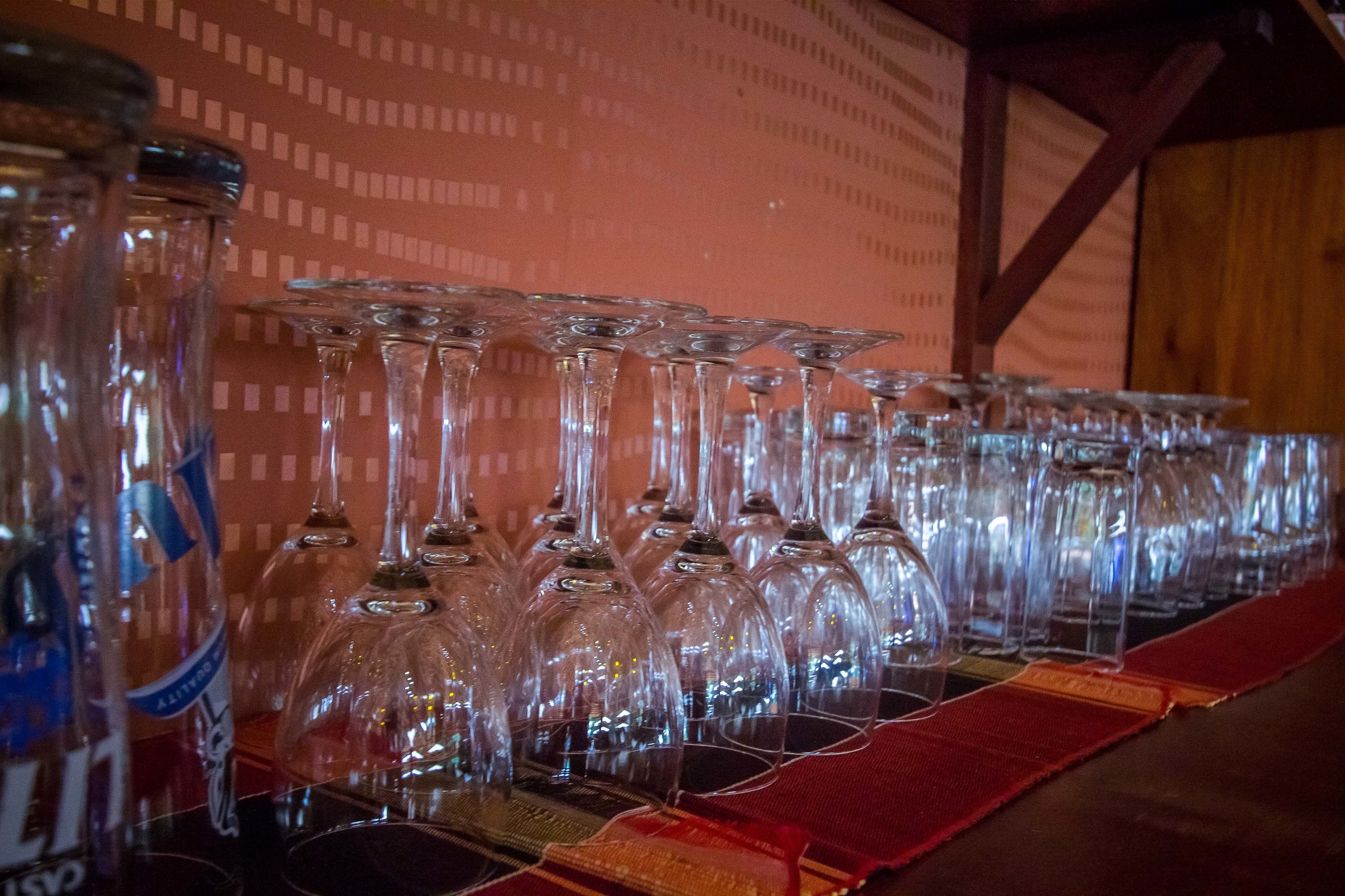 Une rangée de verres à vin vides sur une table recouverte d’une nappe à motifs.