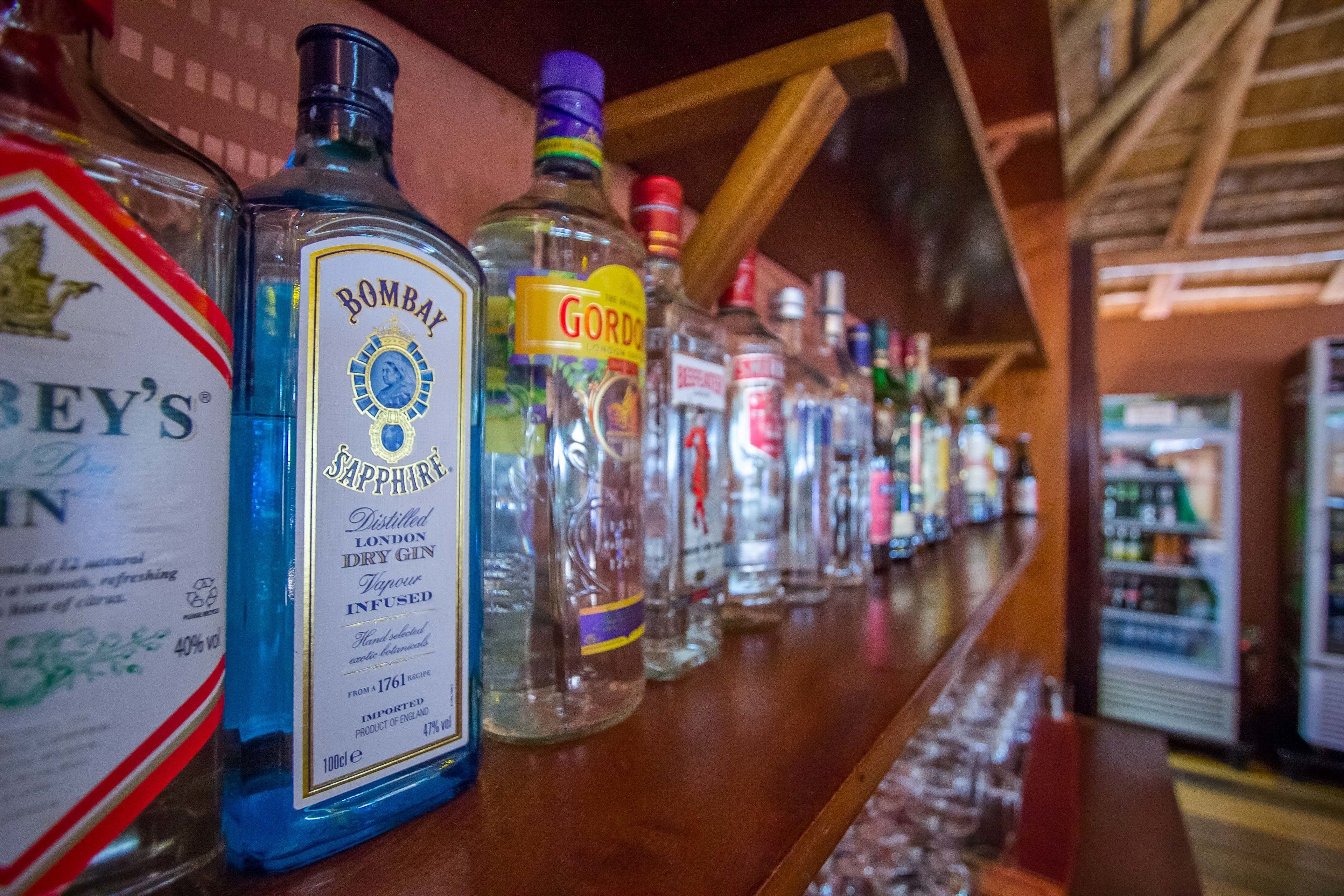 Un bancone bar con diverse bottiglie di liquore, tra cui gin Bombay Sapphire e Gordo.