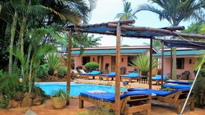 A poolside area with lounge chairs and a wooden pergola. - 2 Friends Guest House (Jinja)