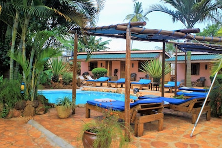 Una piscina al aire libre, sombrillas, sillones reclinables de piscina