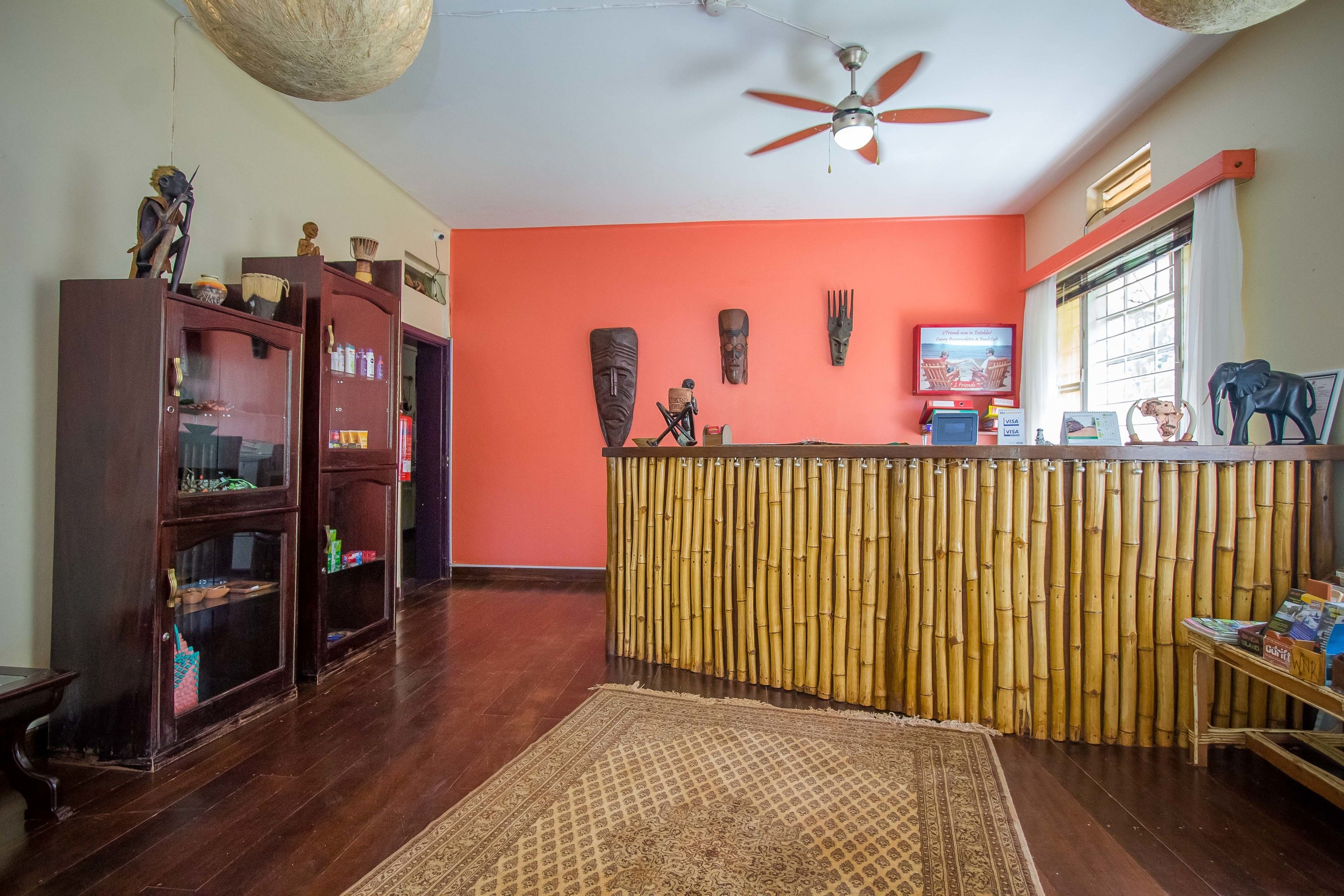 A room with a wooden floor, a ceiling fan, a bamboo partition, and a television on the wall.