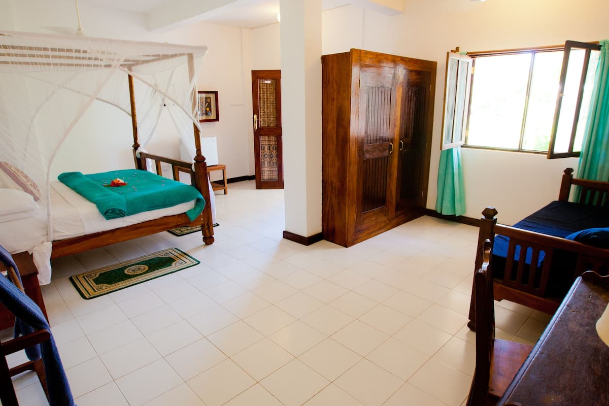 Una habitación con una cama, un armario de madera, una ventana con cortinas y una silla.