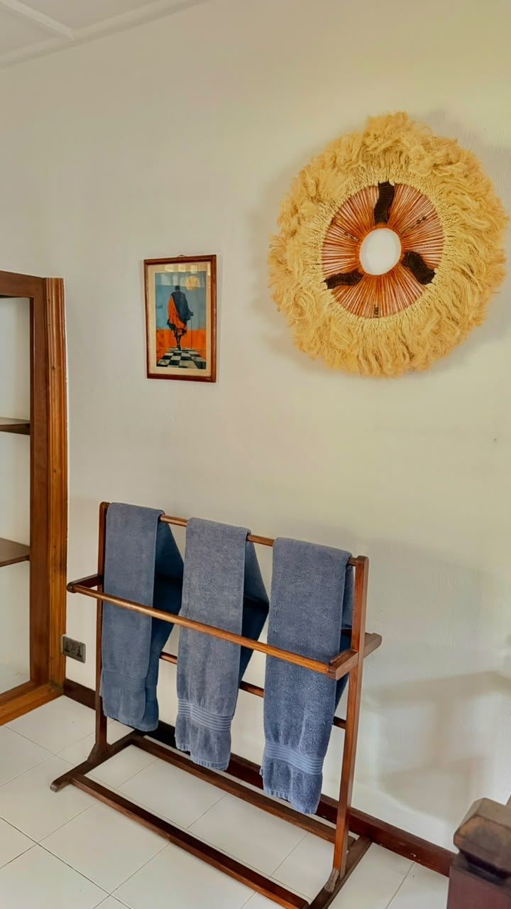 A room with a wooden bench with towels, a wall-mounted decorative item, and a framed picture.