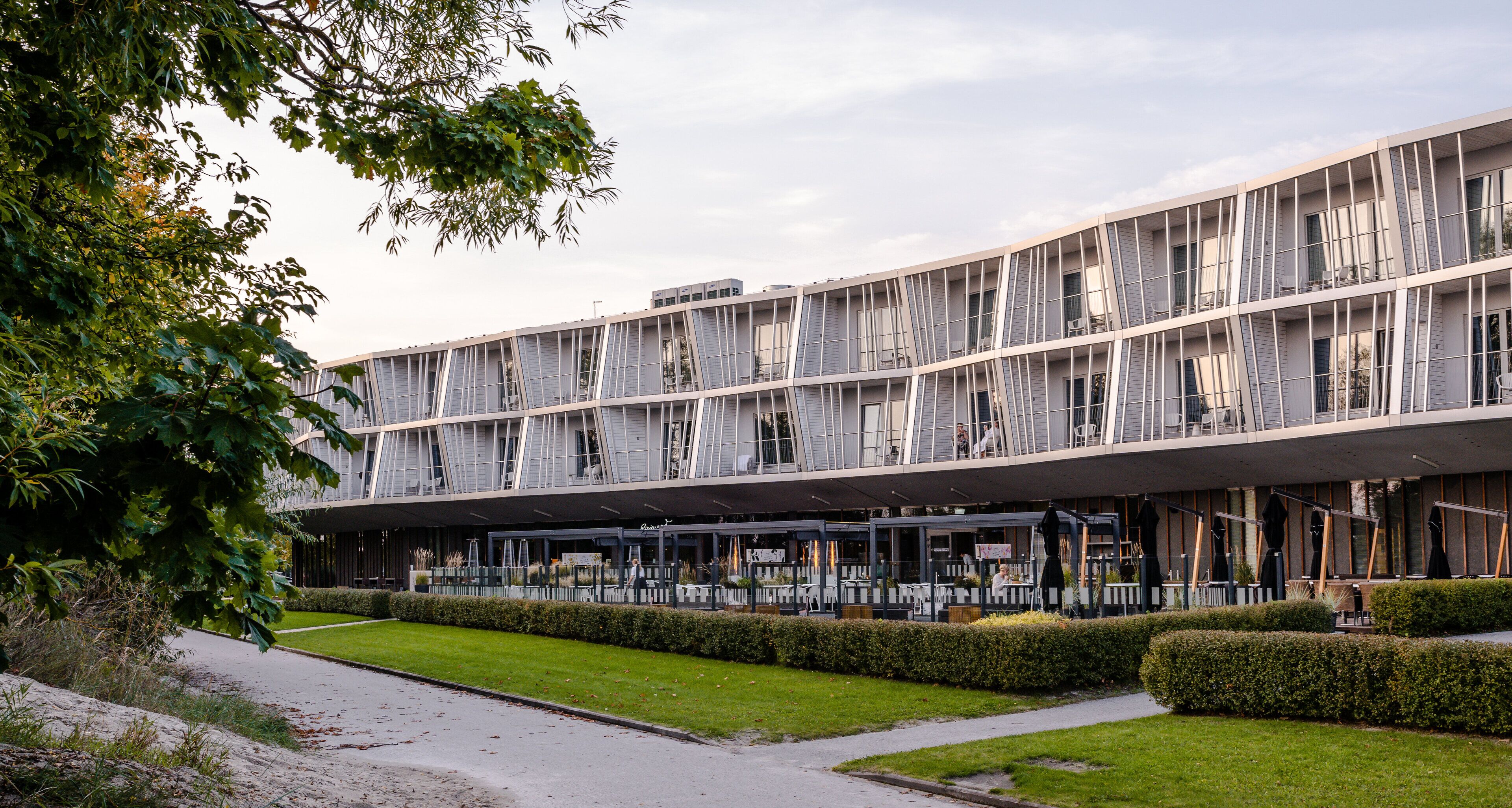 Un edificio moderno con techo plano, amplias ventanas y un área exterior cubierta con asientos.
