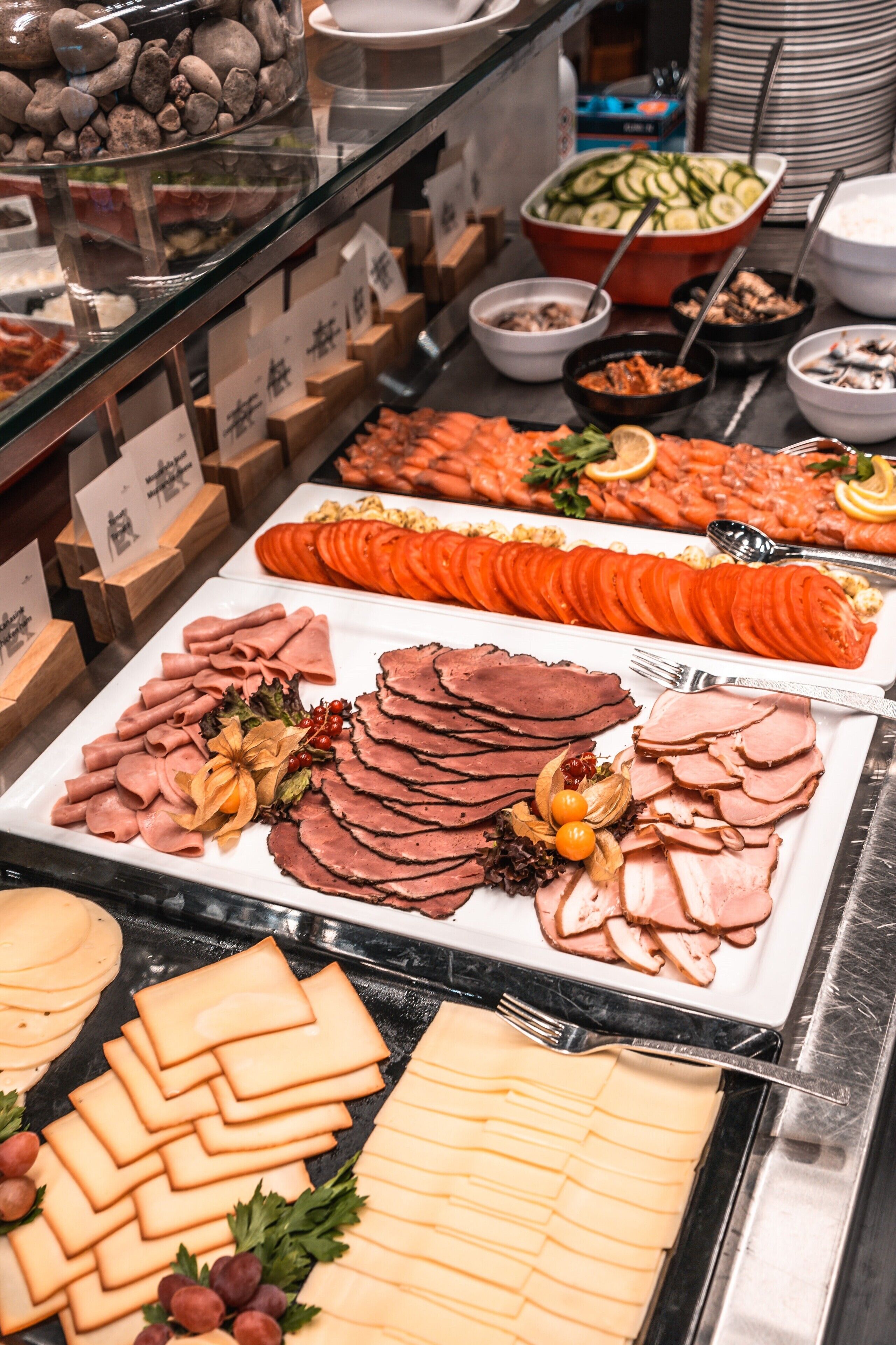Un bufé con una variedad de alimentos, como carnes frías, quesos y verduras.