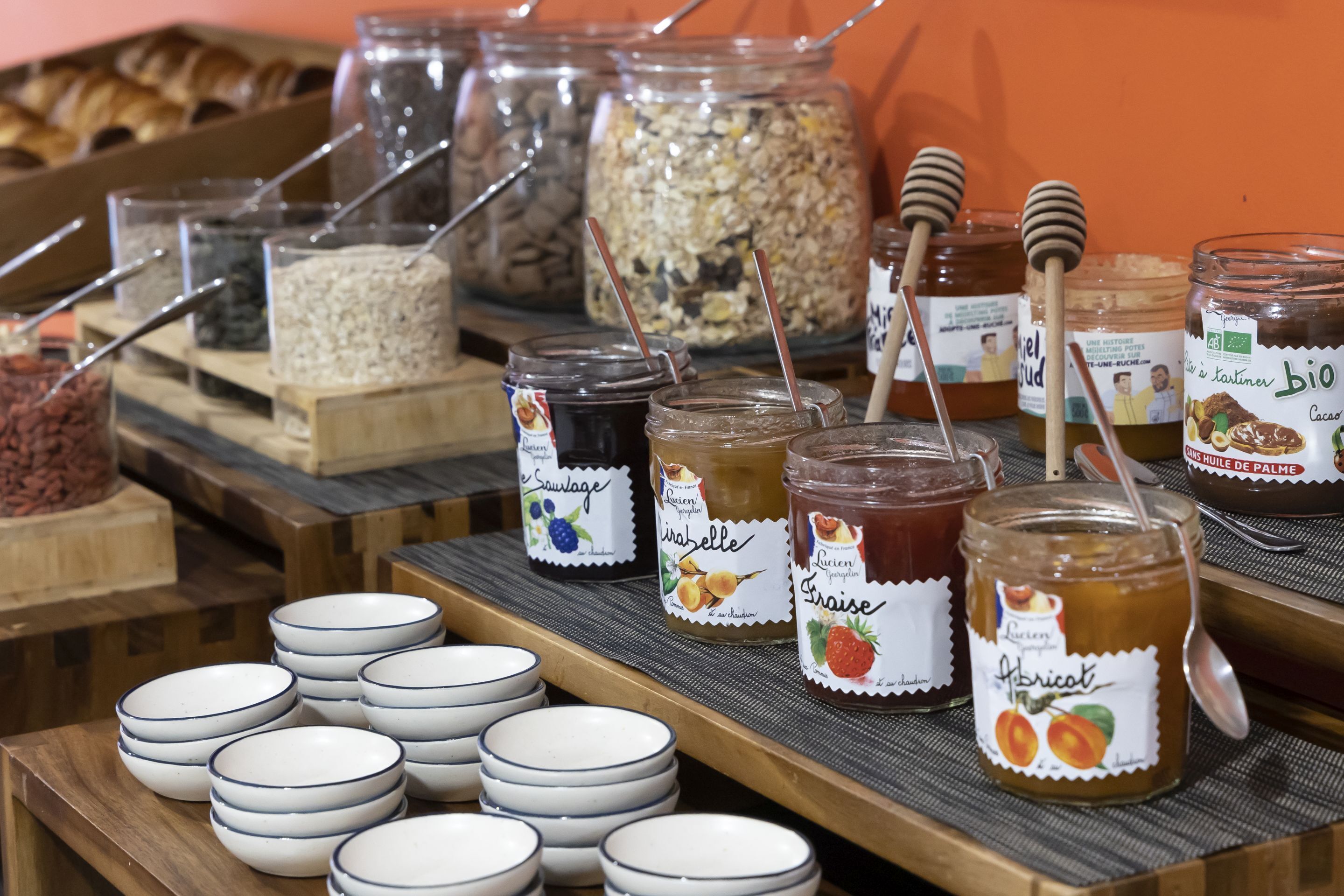 Ein Frühstücksbuffet mit verschiedenen Gläsern mit Brotaufstrichen und Schüsseln mit Müsli.