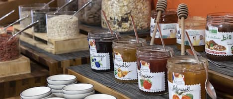 Un buffet de petit-déjeuner proposant divers pots de confitures et des bols de céréales.