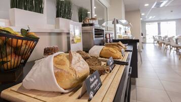 A bakery display with various breads and pastries, a fruit basket, and a sign indicating a pain de campagne.