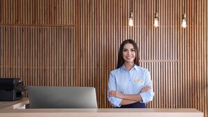 A reception desk with a wooden panel wall, a name tag, and a laptop. - Newcastle Studios (Hersonissos)