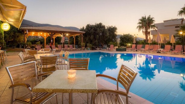 A poolside area with lounge chairs, tables, and a covered seating area. - Newcastle Studios (Hersonissos)