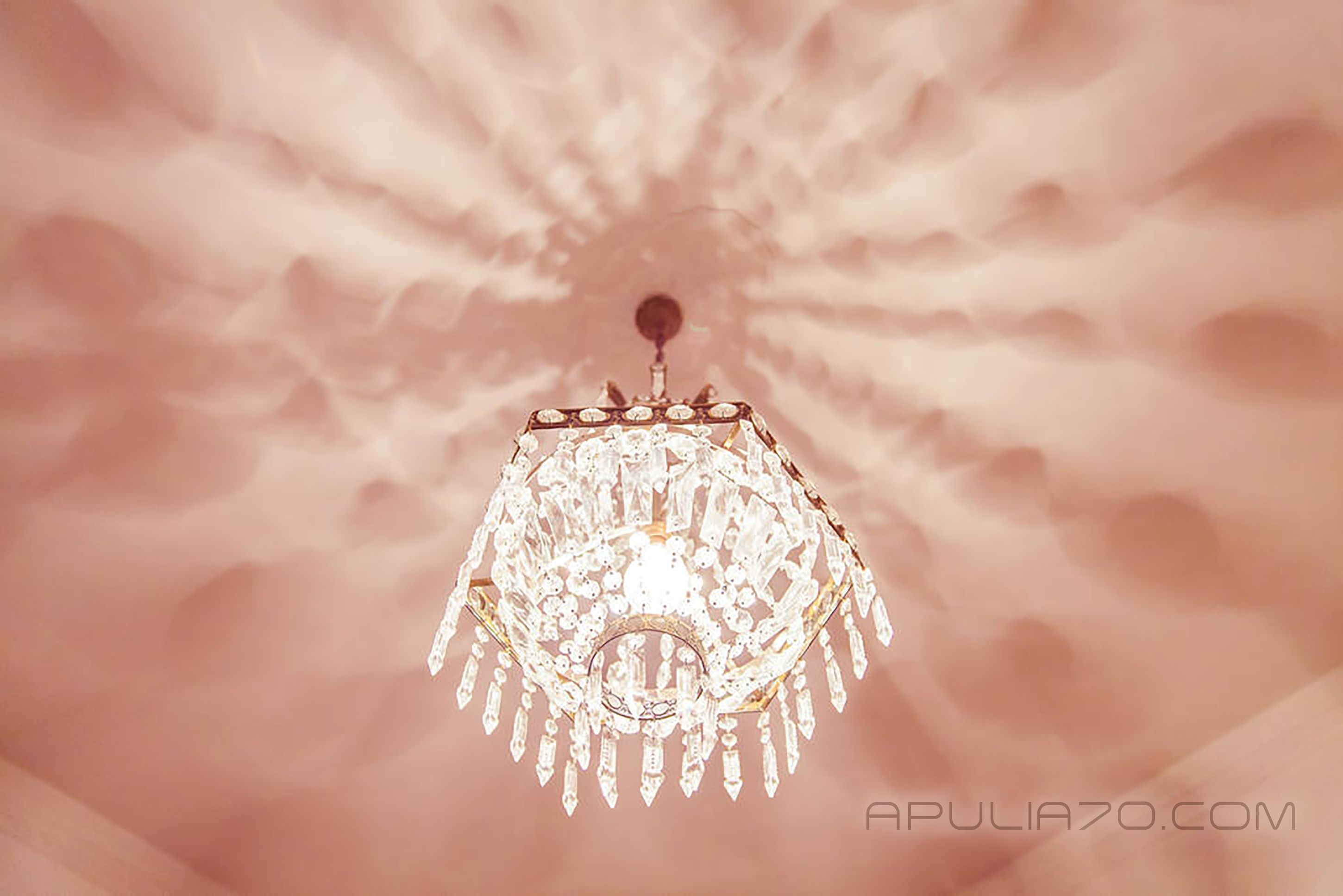 A chandelier with a crystal design hanging from a ceiling with a textured pattern.