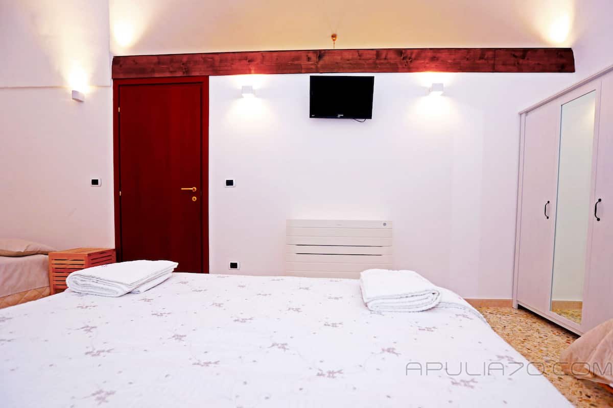 Une chambre à coucher comprenant un lit, une armoire, un téléviseur et un radiateur.