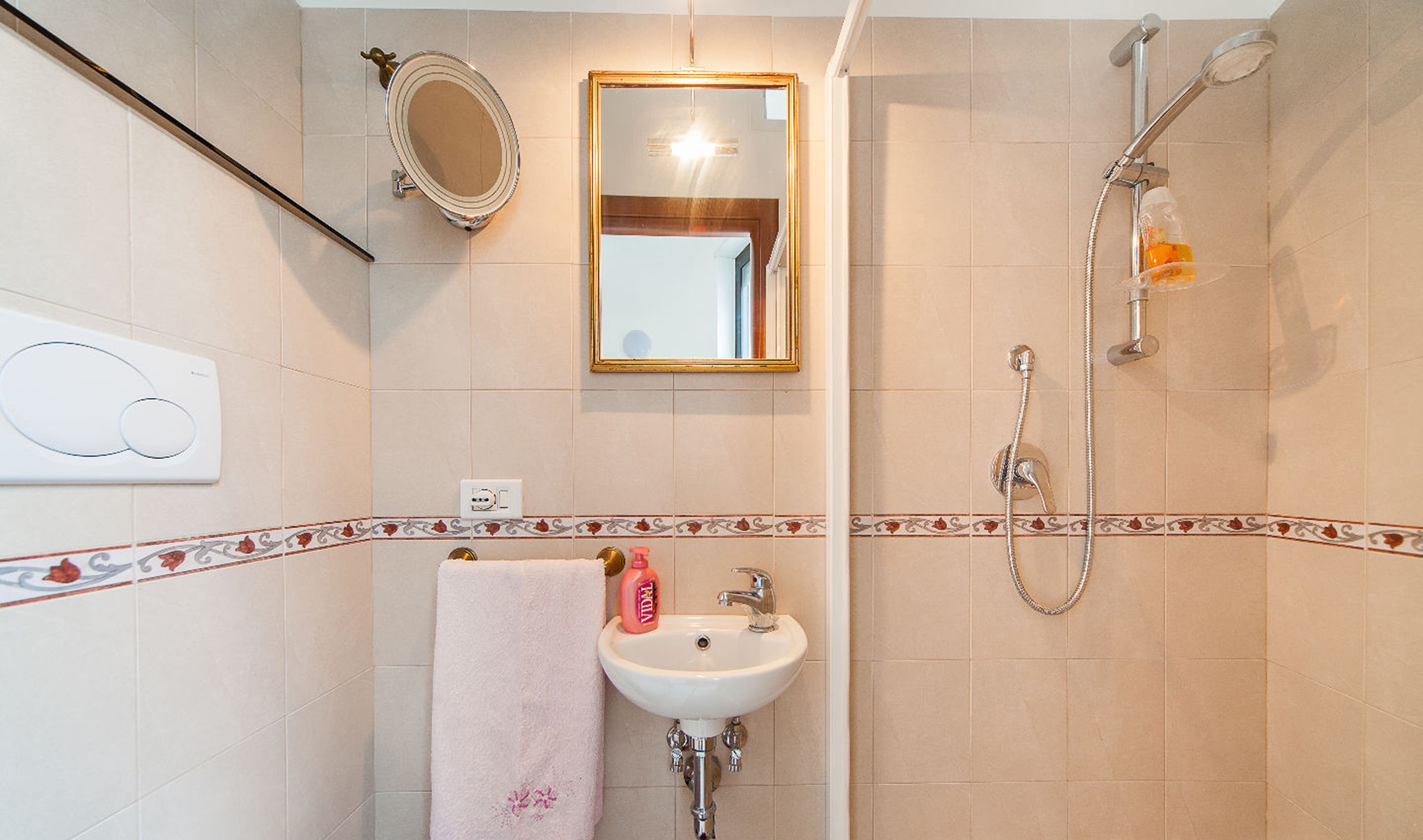 Un baño con lavamanos, espejo y ducha.
