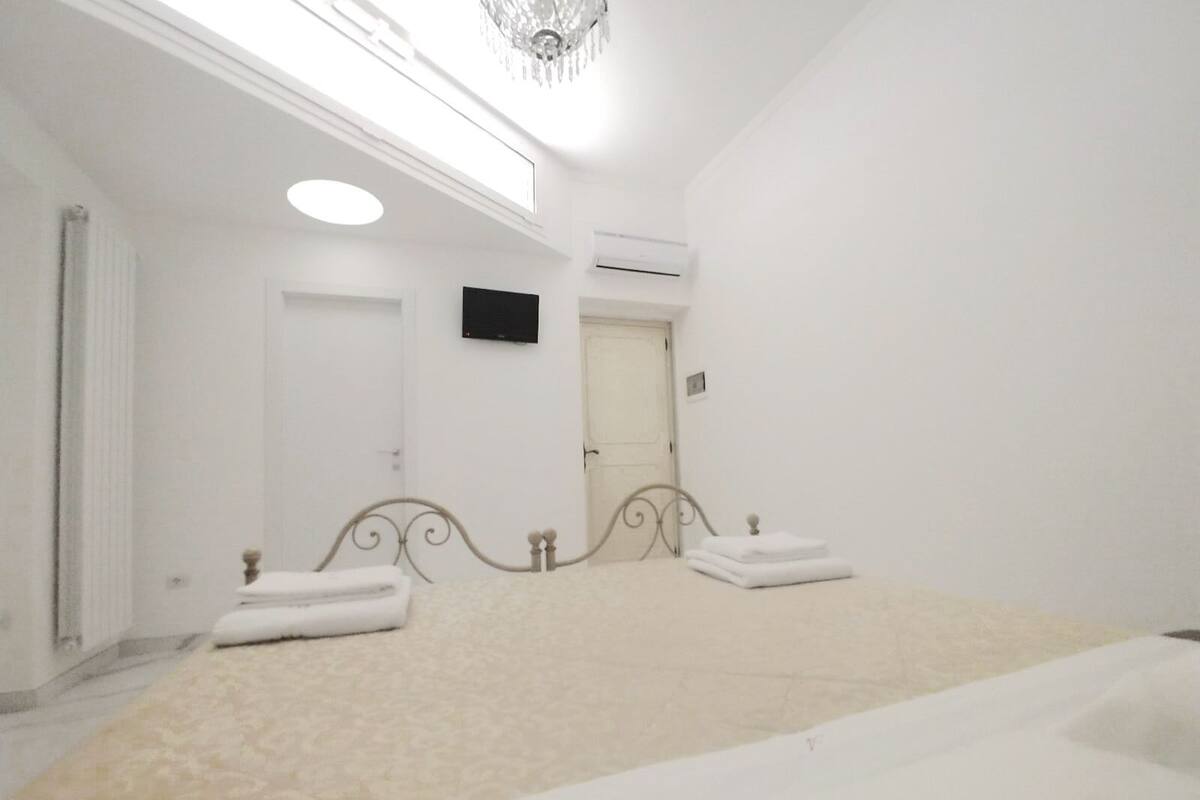 Une chambre à coucher avec un lit, un luminaire au plafond, un appareil de climatisation et une porte.