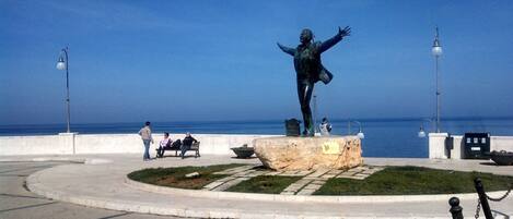 A statue on a raised platform with a clear view of the sea in the background.