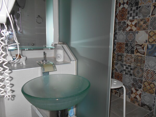 A bathroom with a glass sink, a white toilet, and a shower area. - La Veranda of Mykonos (Mykonos)