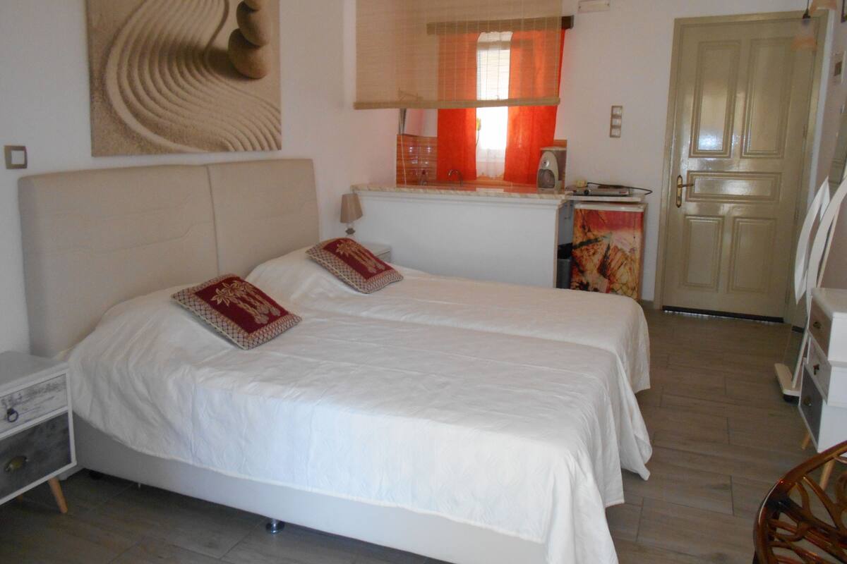 A bedroom with two beds, a desk, a chair, and a door.
