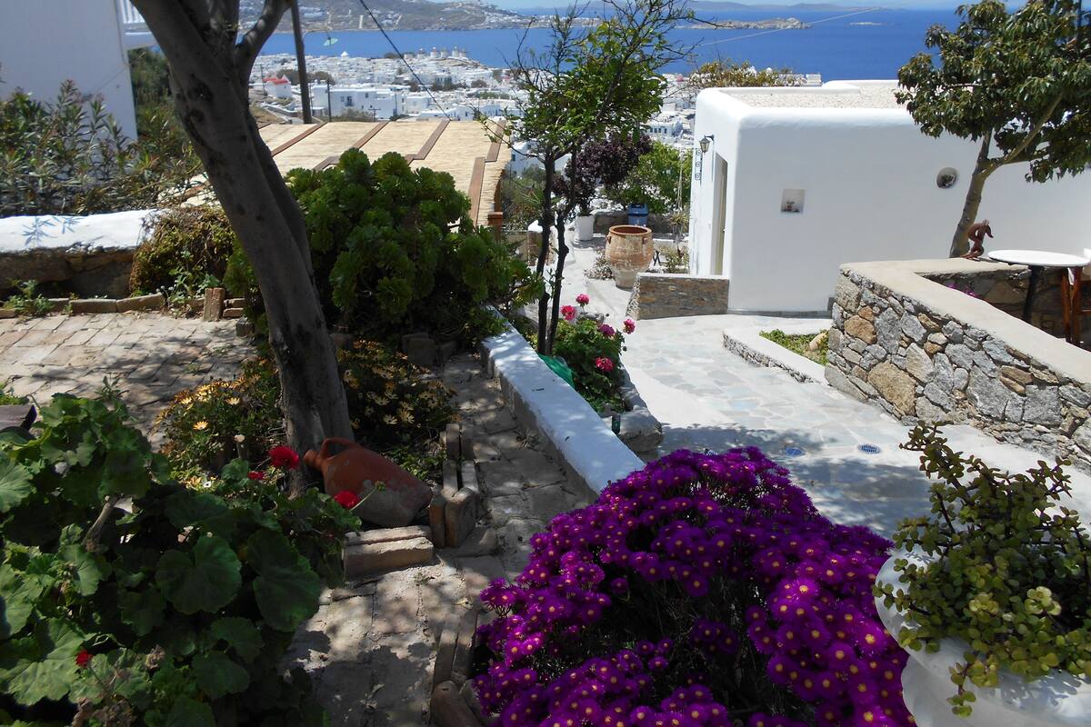 A white-washed building with a stone wall and a view of the sea.