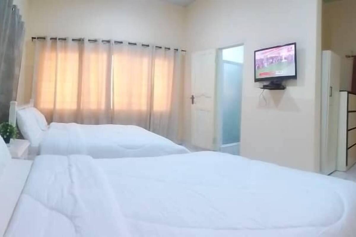 Una habitación de hotel con dos camas, un televisor y un espejo.