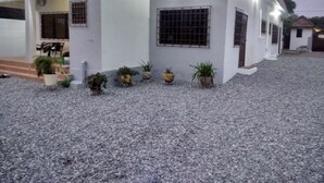 Un bâtiment avec une allée gravillonnée, des plantes en pot et une entrée fermée par un portail.