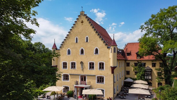 A large, yellow building with a steeply pitched roof and multiple windows. - Schloss zu Hopferau (Hopferau)