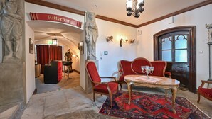 A lobby with a red carpet, a statue, a chandelier, and a table with chairs. - Schloss zu Hopferau (Hopferau)