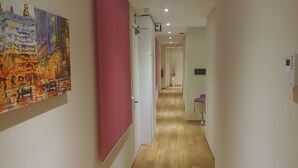 A hallway with a wooden floor, a red partition, and a painting on the left wall. - Hostal Barcelona Travel (Barcelona)