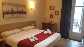 A hotel room with a large bed, a desk, a chair, a cityscape painting, and a window with a view. - Hostal Barcelona Travel (Barcelona)