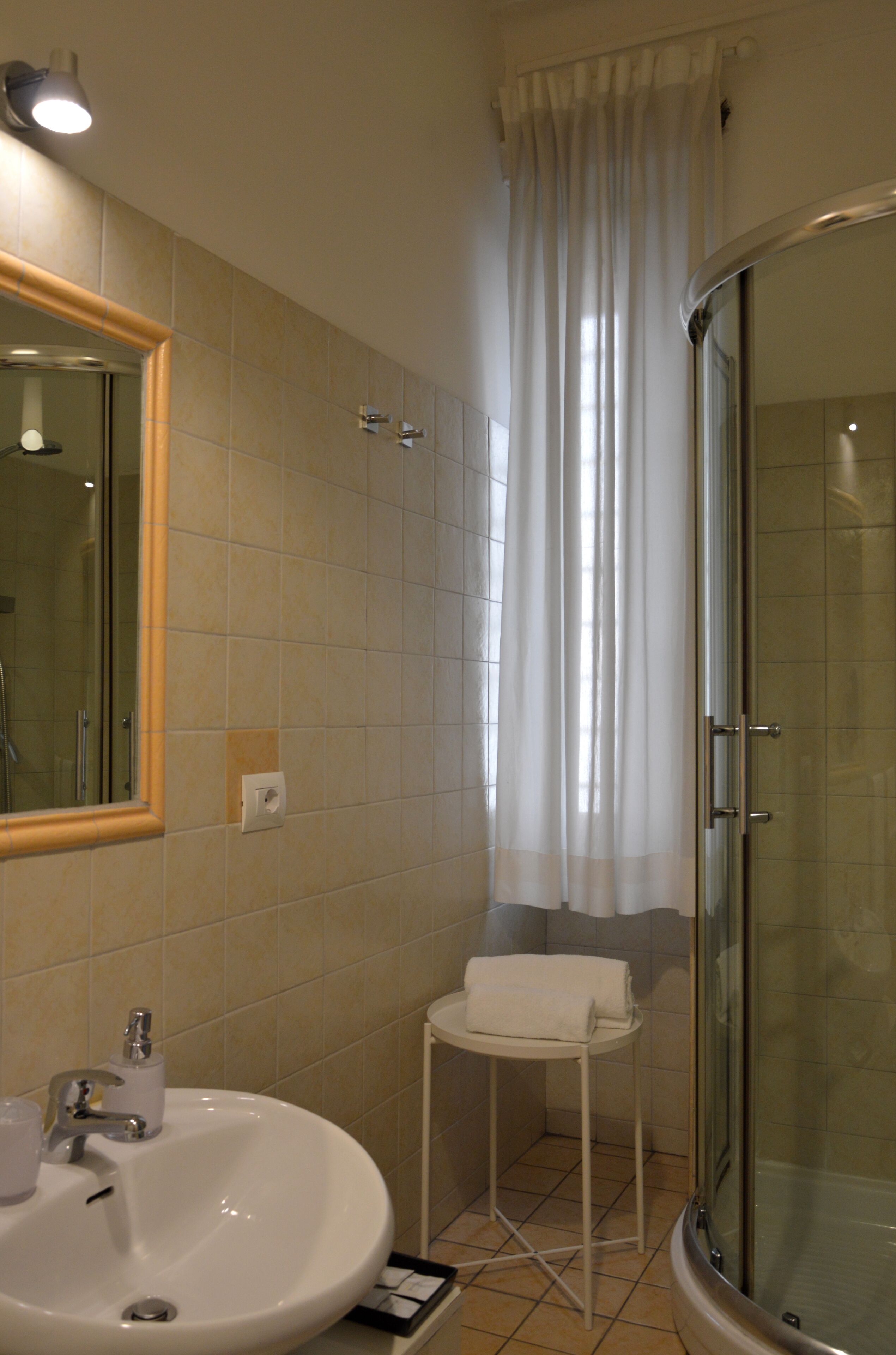 A bathroom with a sink, mirror, and shower.