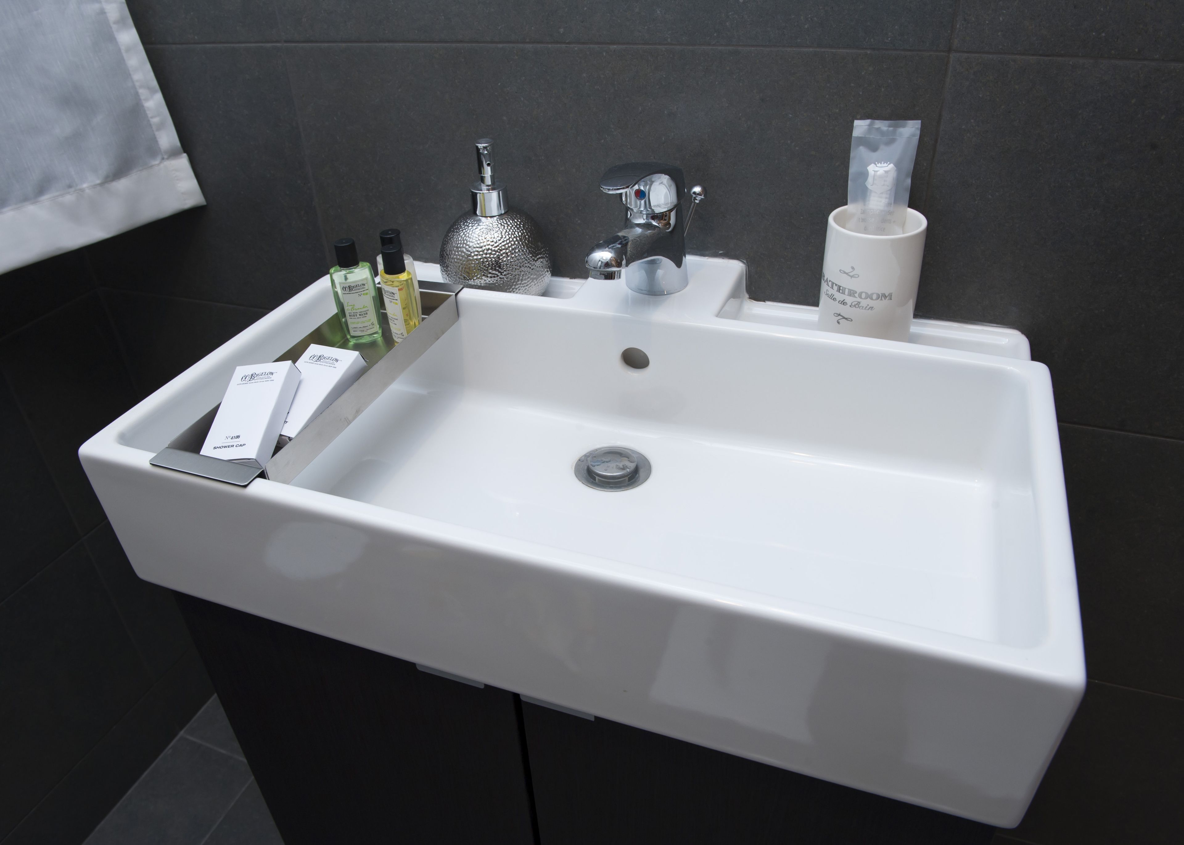 A white bathroom sink with a silver faucet, a soap dispenser, and a bottle of liquid soap.