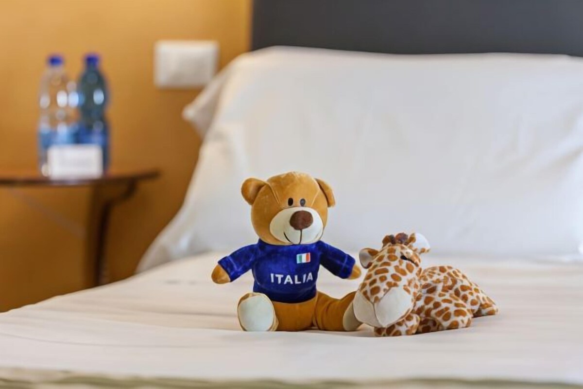 A bed with a teddy bear and a giraffe toy on it.